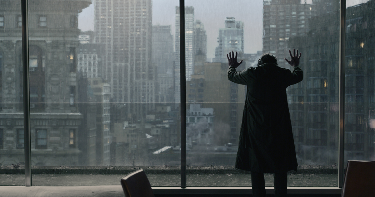 A still of Doctor Strange with his hands against tall glass windows looking out over a city